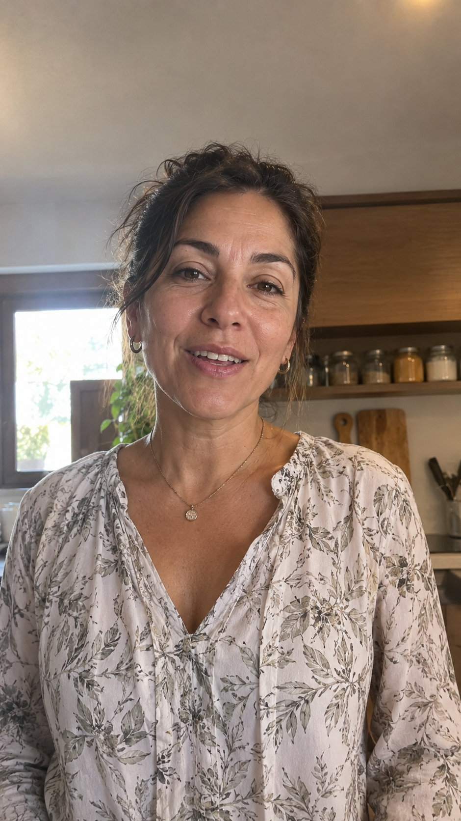 Mujer adulta con blusa estampada hablando a cámara en la cocina de su casa